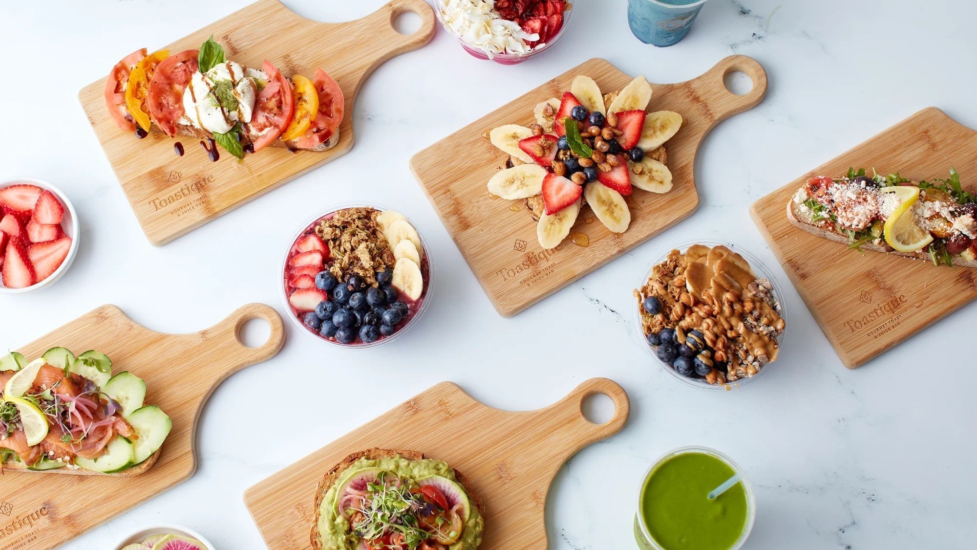 High-protein gourmet toasts, smoothie bowls, and smoothies at Toastique restaurant in Porter Ranch displayed on wooden boards