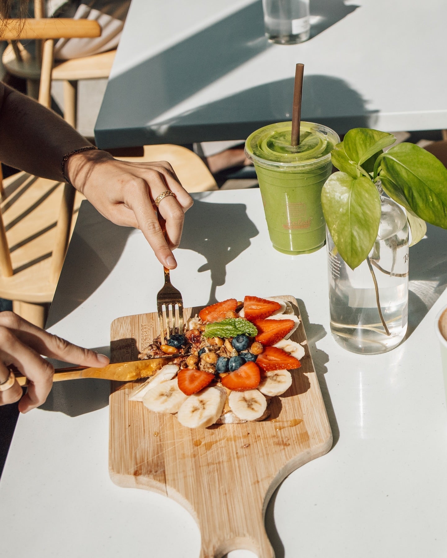 Healthy breakfast with fresh fruit-topped toast and a green smoothie on a sunny café table, highlighting the vibrant and nutritious breakfast options in Addison, TX.
