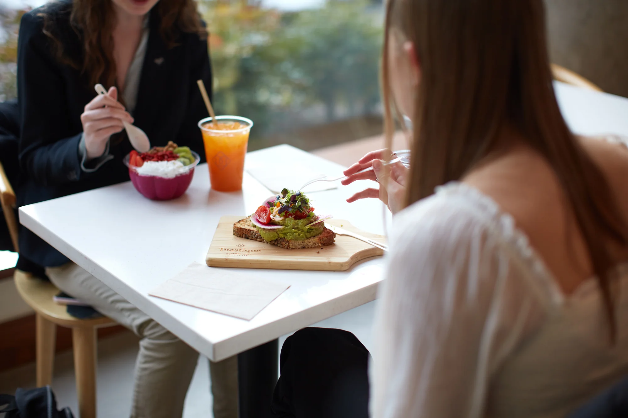 Guests enjoying avocado toast, a smoothie bowl, and a fresh-made juice, capturing the café’s bright, handcrafted approach to coffee and healthy breakfast.