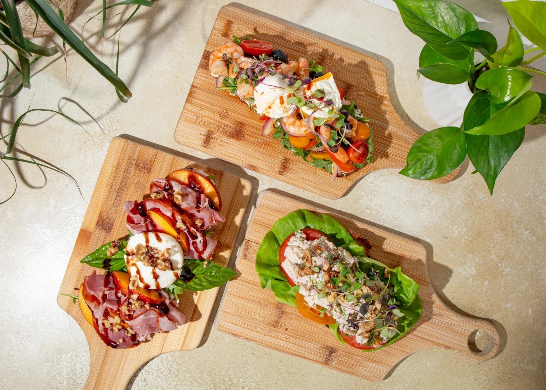 Assorted Toastique gourmet toasts topped with fresh ingredients on wooden serving boards.