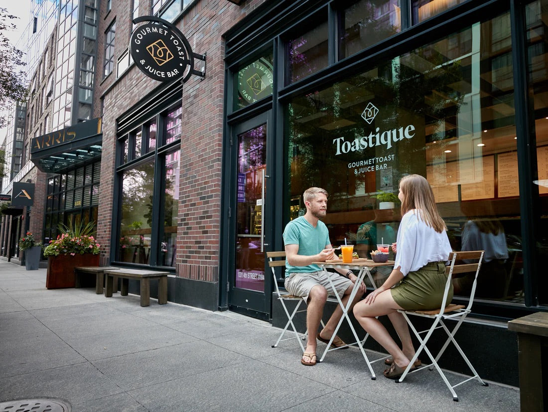 Guests enjoying smoothie bowls and juices outside a Toastique café, showcasing a breakfast and brunch franchise that draws community together.