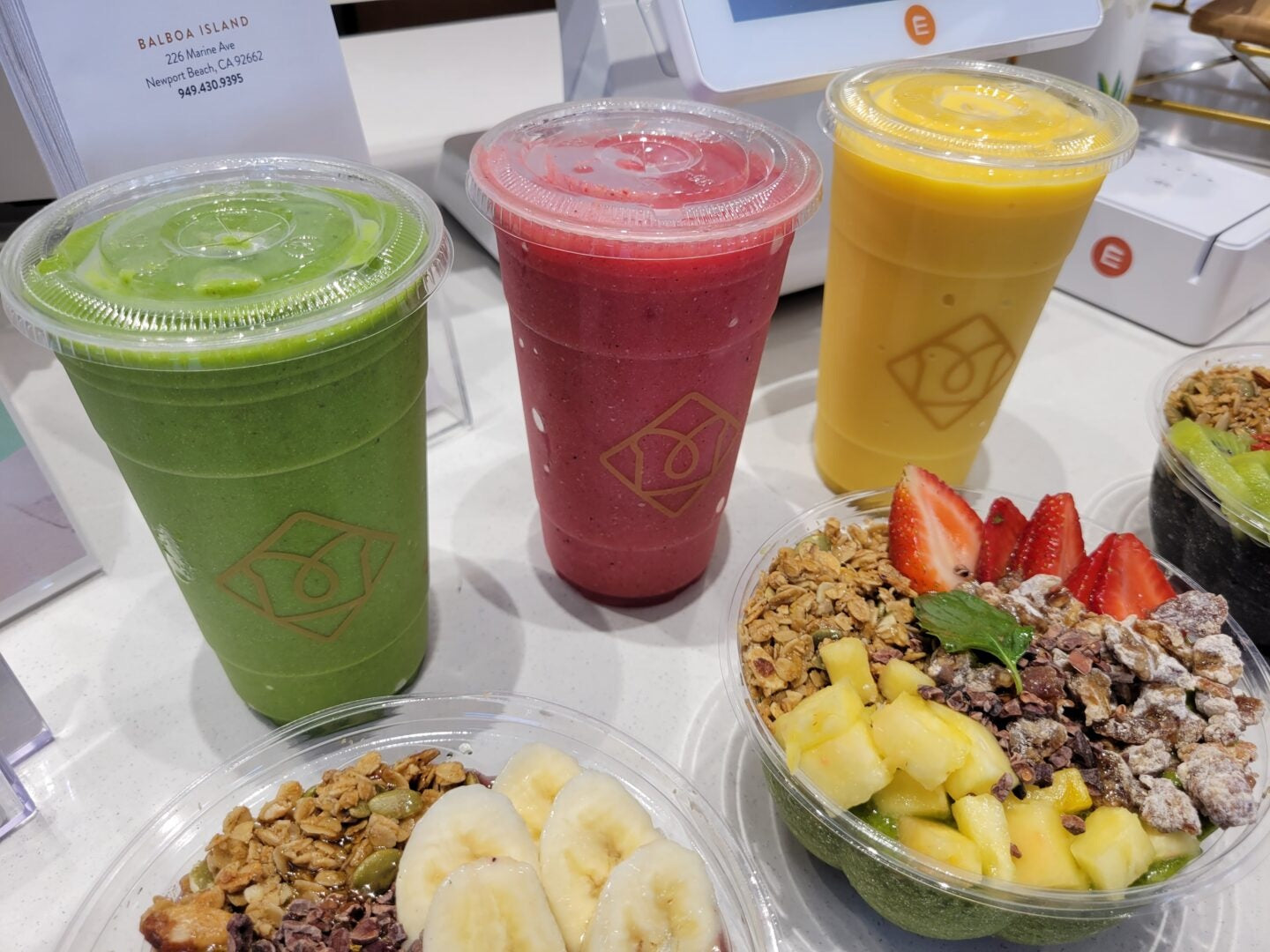 Colorful smoothies and smoothie bowls topped with bananas, strawberries, pineapple, and granola, displayed inside a Toastique smoothie franchise café