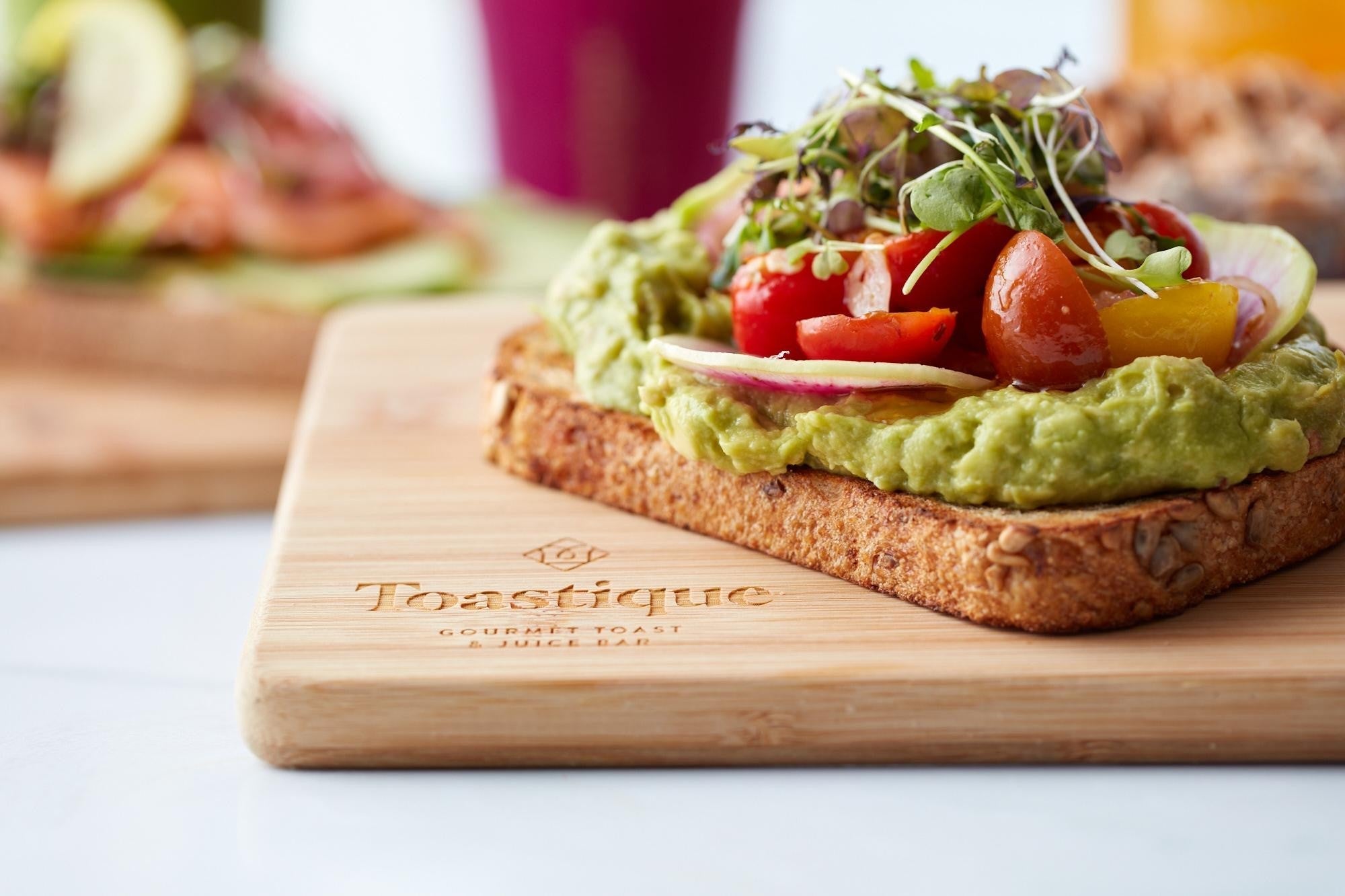 Close-up of the perfect toast: avocado smash with marinated tomatoes, chili oil, microgreens on multigrain toast at Toastique Raleigh.