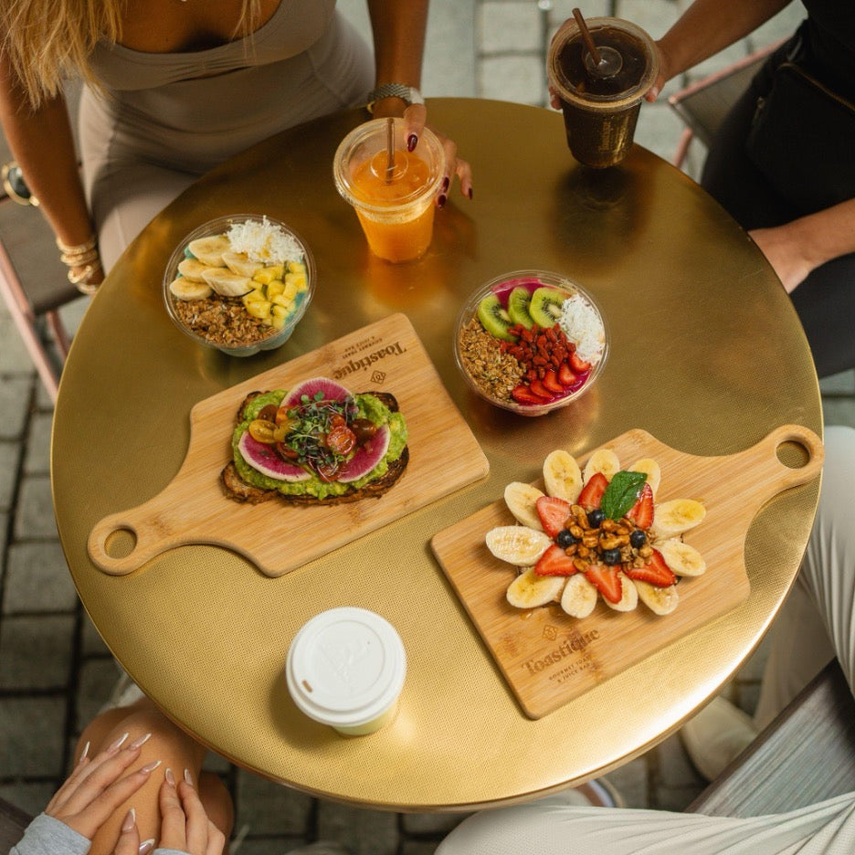Anti-inflammatory breakfast spread at Toastique featuring avocado toast, acai and pitaya bowls with berries and kiwi, fresh-pressed juice, and coffee.  