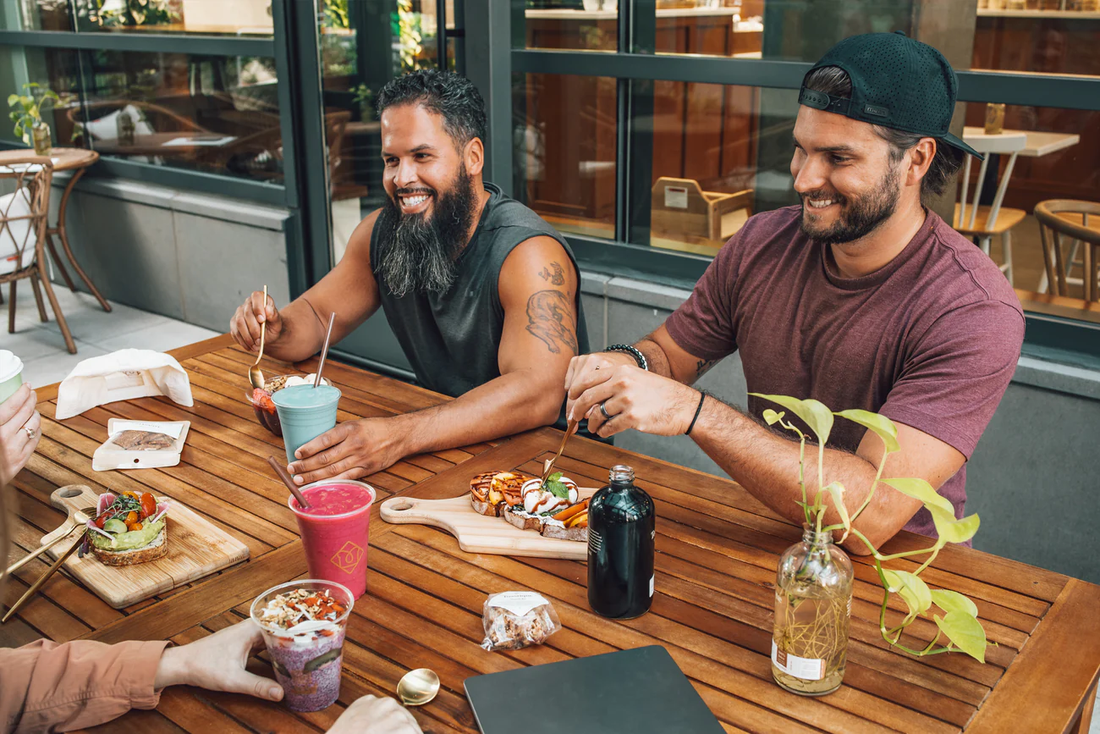 Friends enjoying Toastique smoothies and gourmet toast at an outdoor café table.