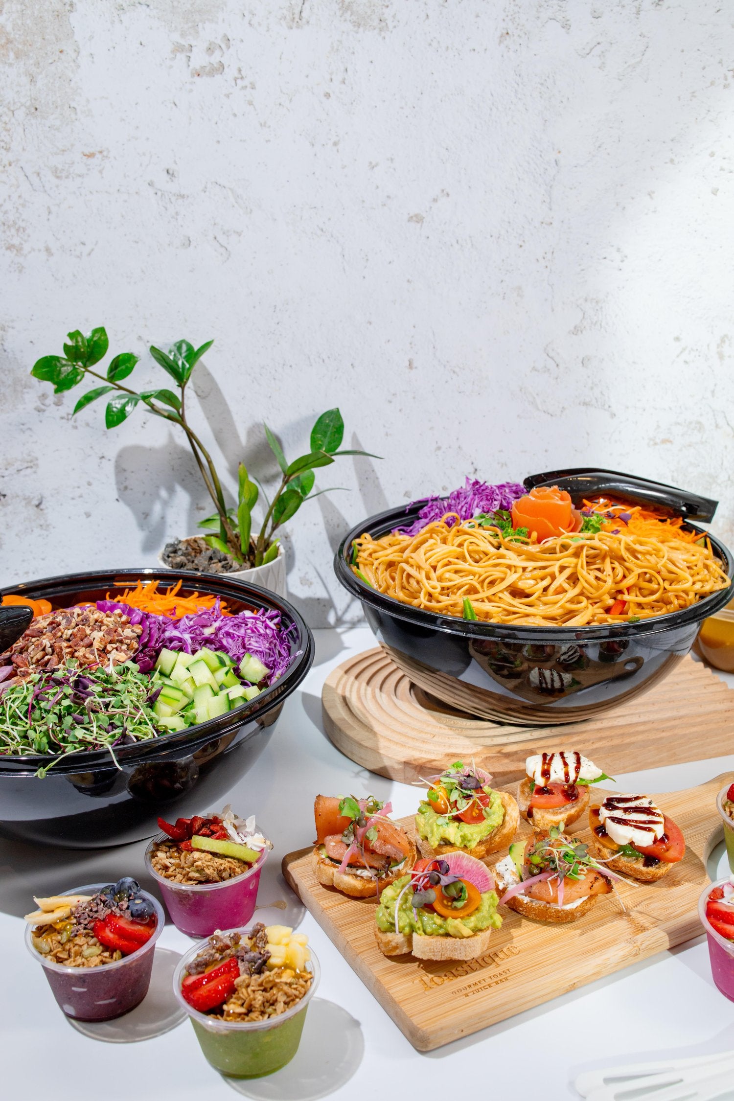 Toastique catering spread with grain bowls, noodle bowls, gourmet toast bites and smoothie cups