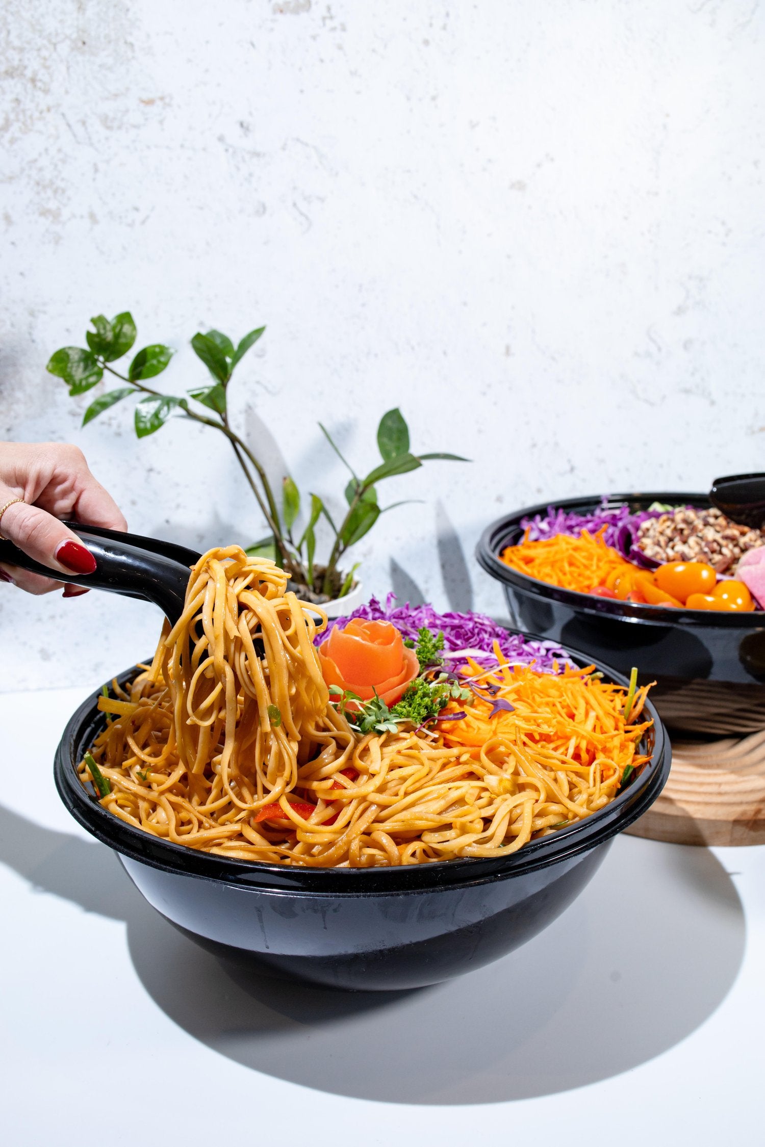 Toastique catering noodle dish served in a black bowl on a marble table