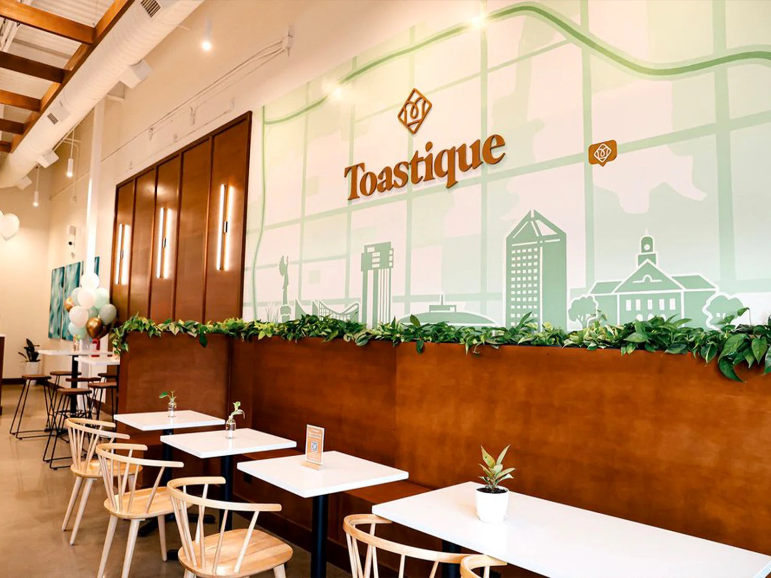 Inside a Toastique coffee bar franchise featuring boutique coffee bar design with warm seating, greenery, and modern branding that attracts health-focused guests.