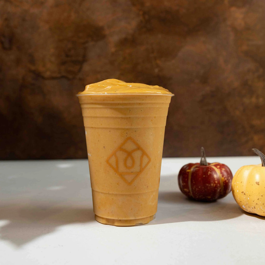 Toastique's Spiced Pumpkin Smoothie on a table with pumpkins in the backgrund.